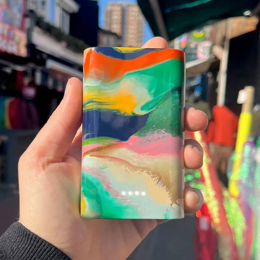 Hand holding a Gomi power bank with a bold, swirled design made from recycled plastic waste