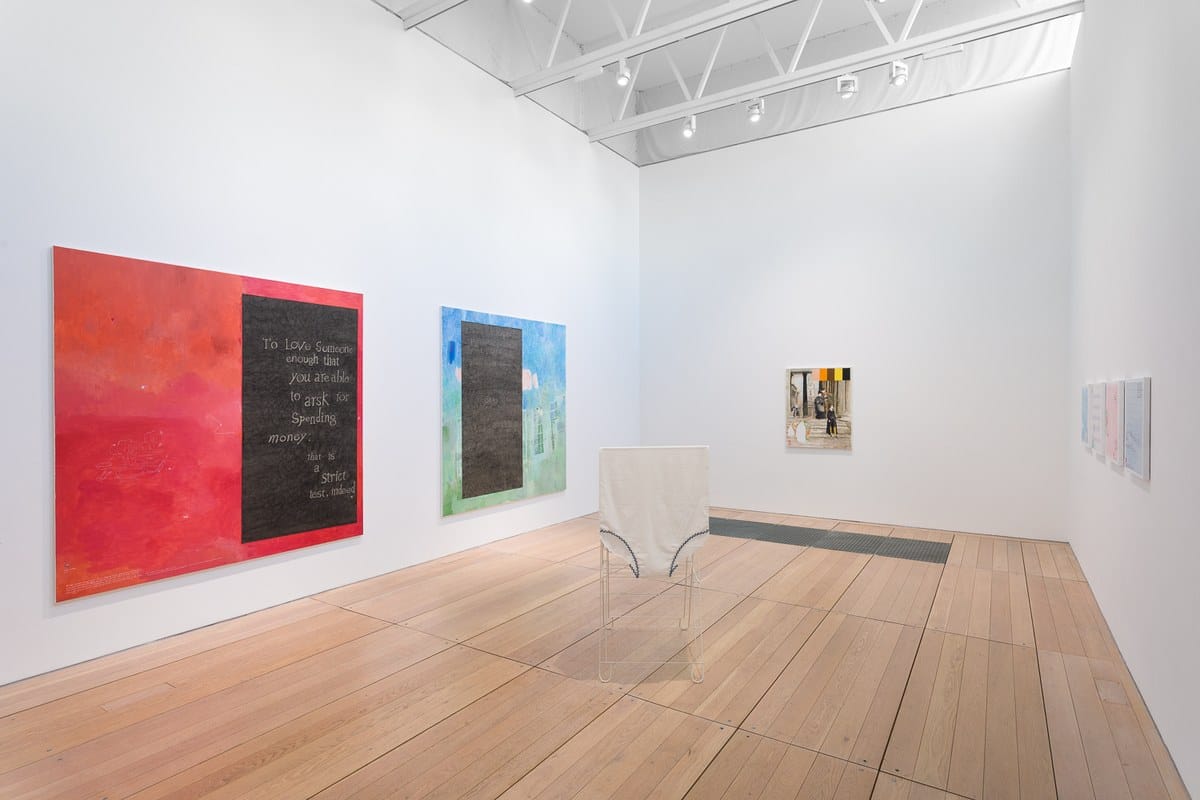 Large red and blue paintings with handwritten text and a small sculpture in a top-lit gallery at Goldsmiths CCA