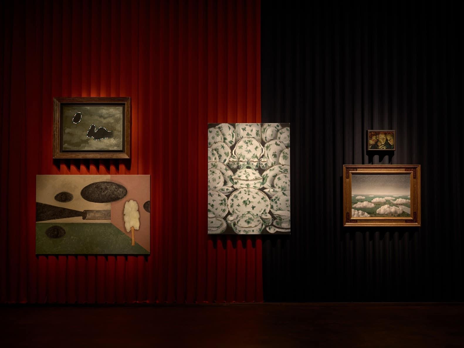 Paintings by Magritte, Pol Taburet, Issy Wood and Victor Man hung on red and black curtains