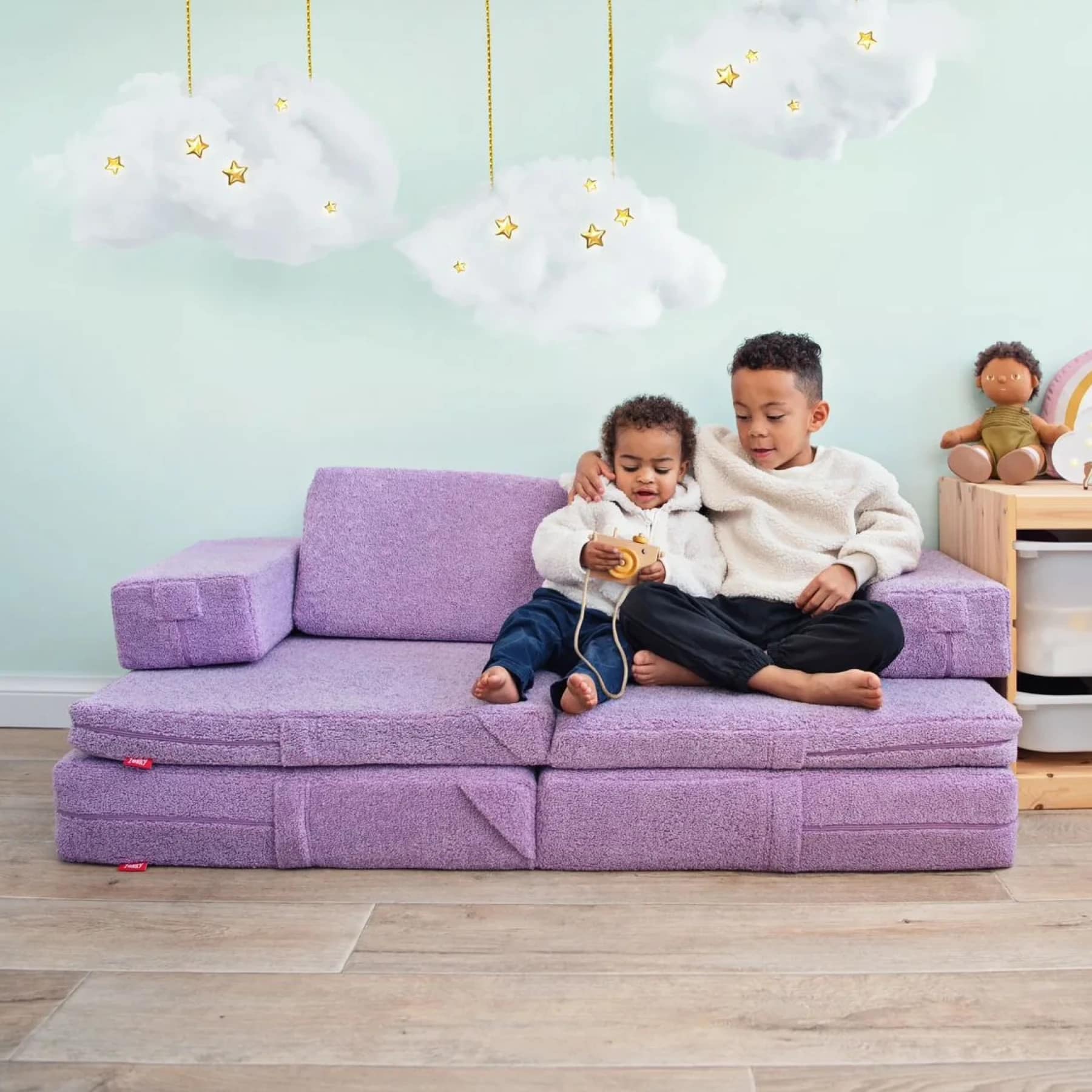 Two children sitting on a purple Zonky play sofa modular kids play couch in a nursery