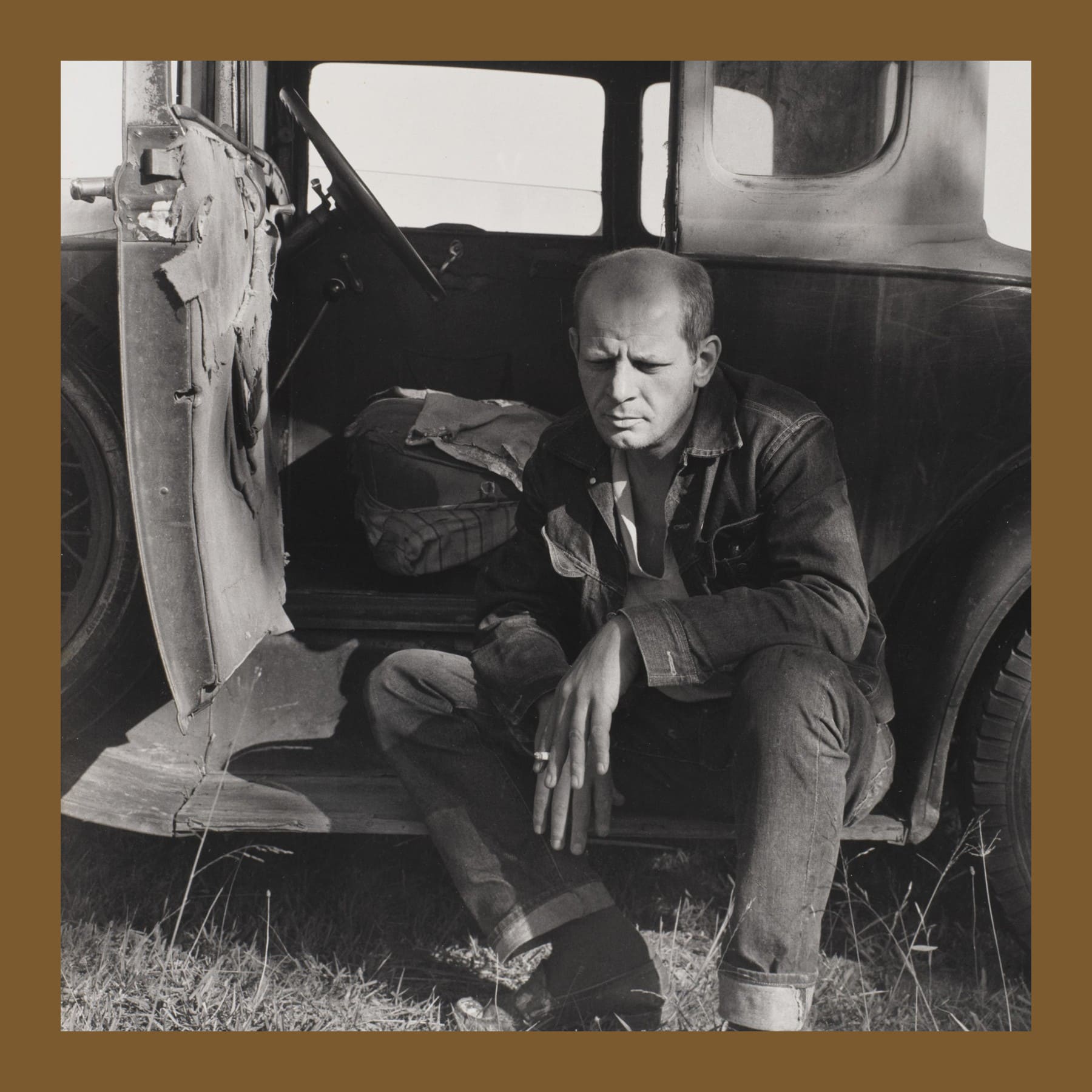 Black and white photo of Jackson Pollock sitting in the open door of an old car