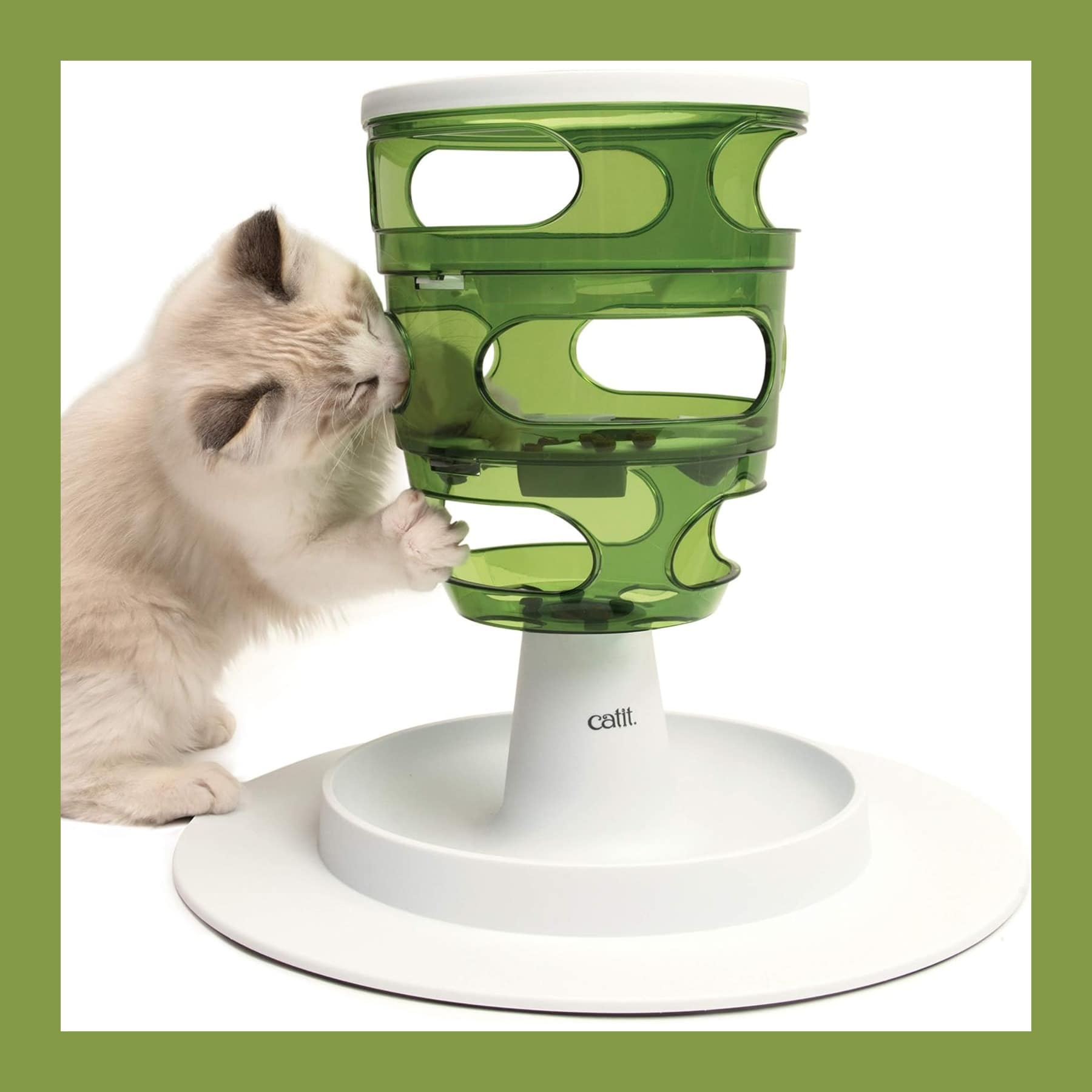 Catit Senses 2.0 Food Tree slow feeder with a green tower on a white tray and a kitten pawing at it