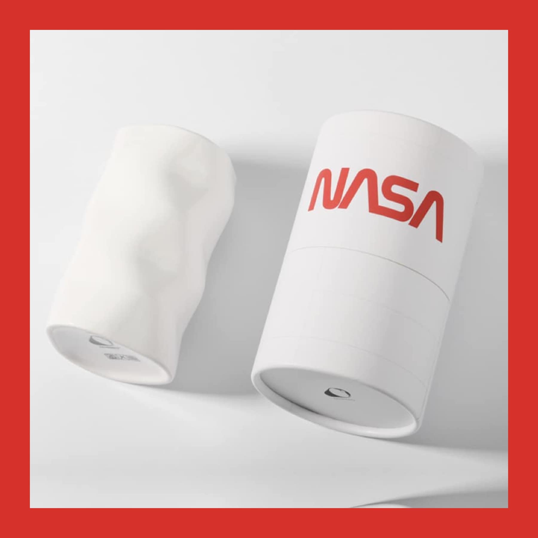 White sculpted ceramic mug beside a white cylinder printed with the red NASA worm logo