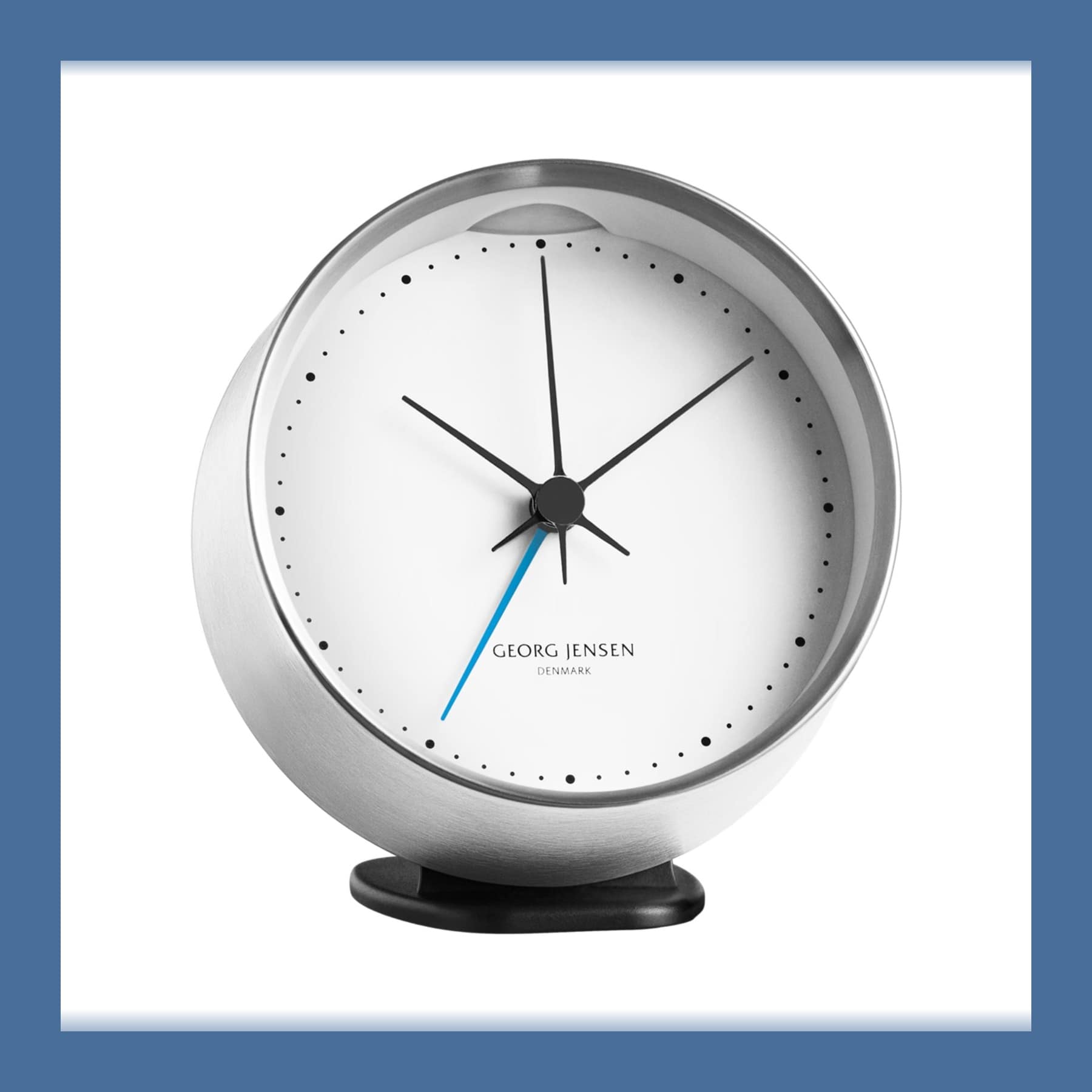Georg Jensen Koppel alarm clock in its black stand, white dial with black hands and a blue second hand in a polished steel case