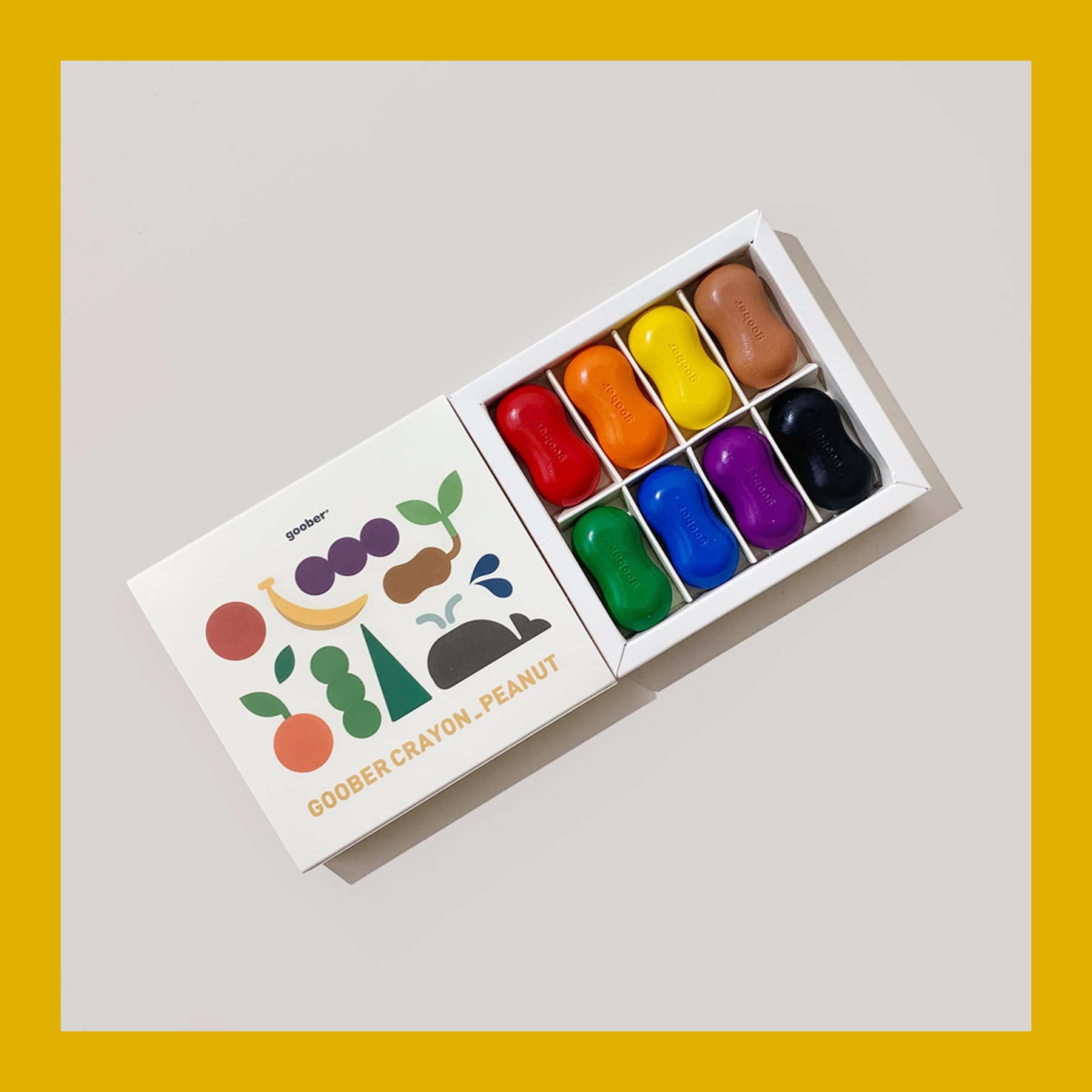 Goober peanut-shaped crayons in eight colours in an open white box with an illustrated lid