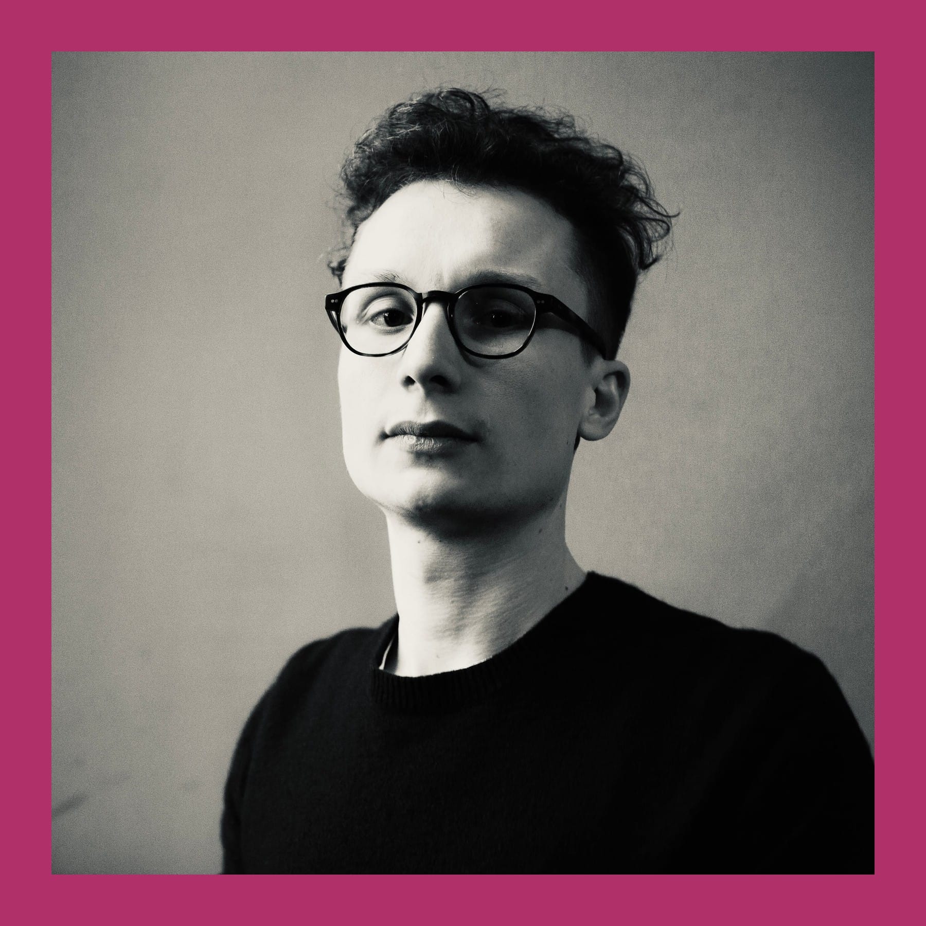 Black and white portrait of Stiven Skyrah in round glasses and a dark jumper