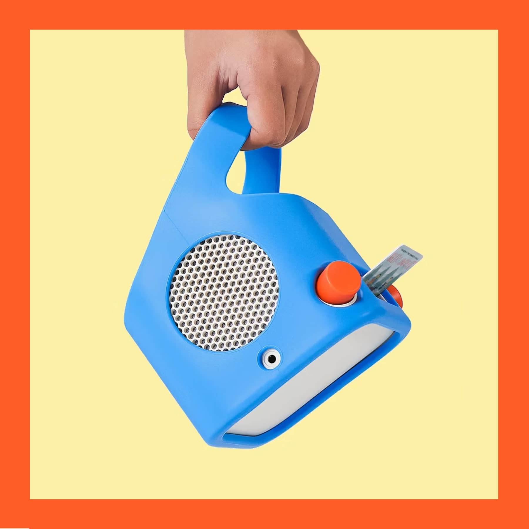 A hand holding a Yoto Player in a blue Adventure Jacket, inserting a Yoto card into the top slot