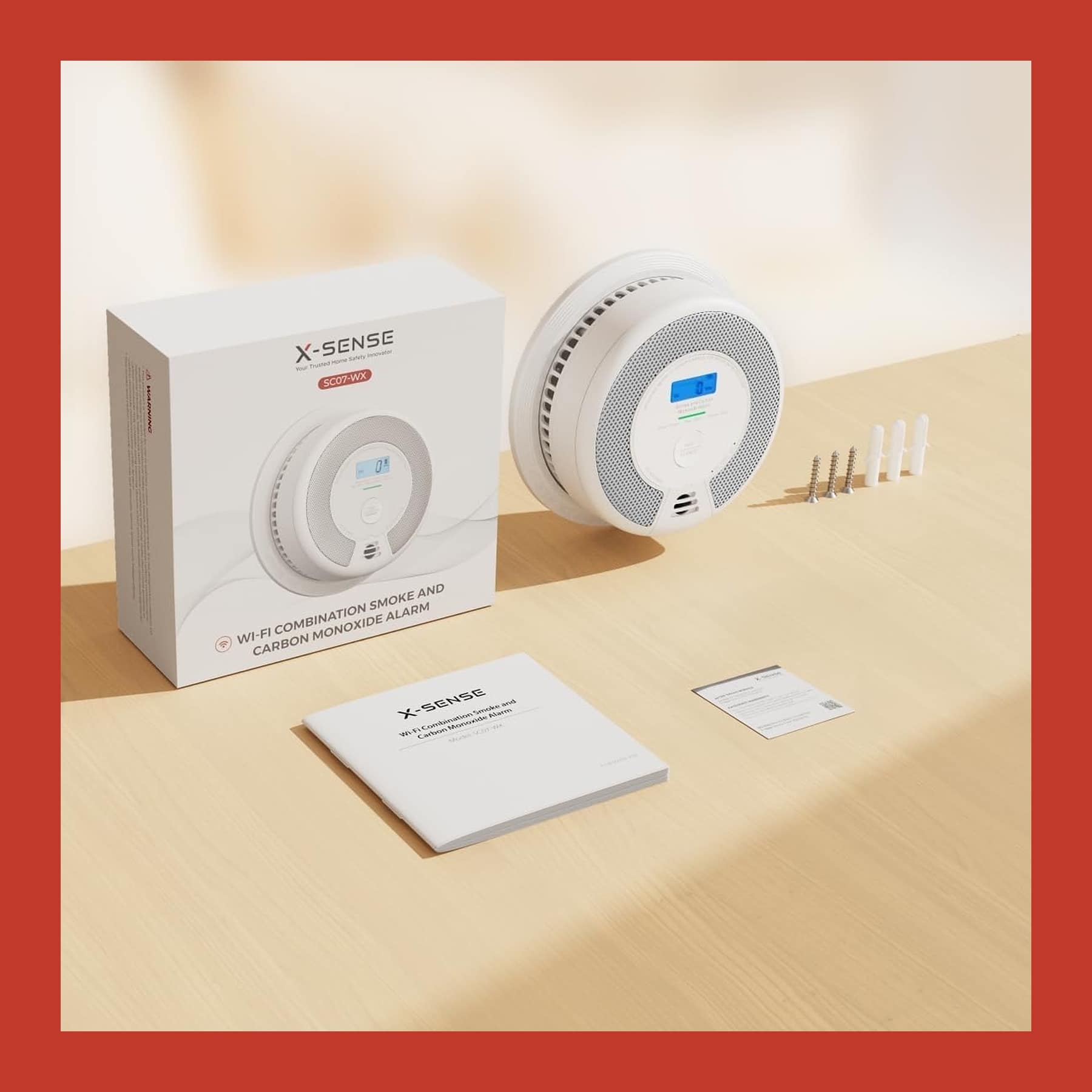 X-Sense SC07-WX Wi-Fi smoke and carbon monoxide alarm on a table with its box, manual and wall fixings