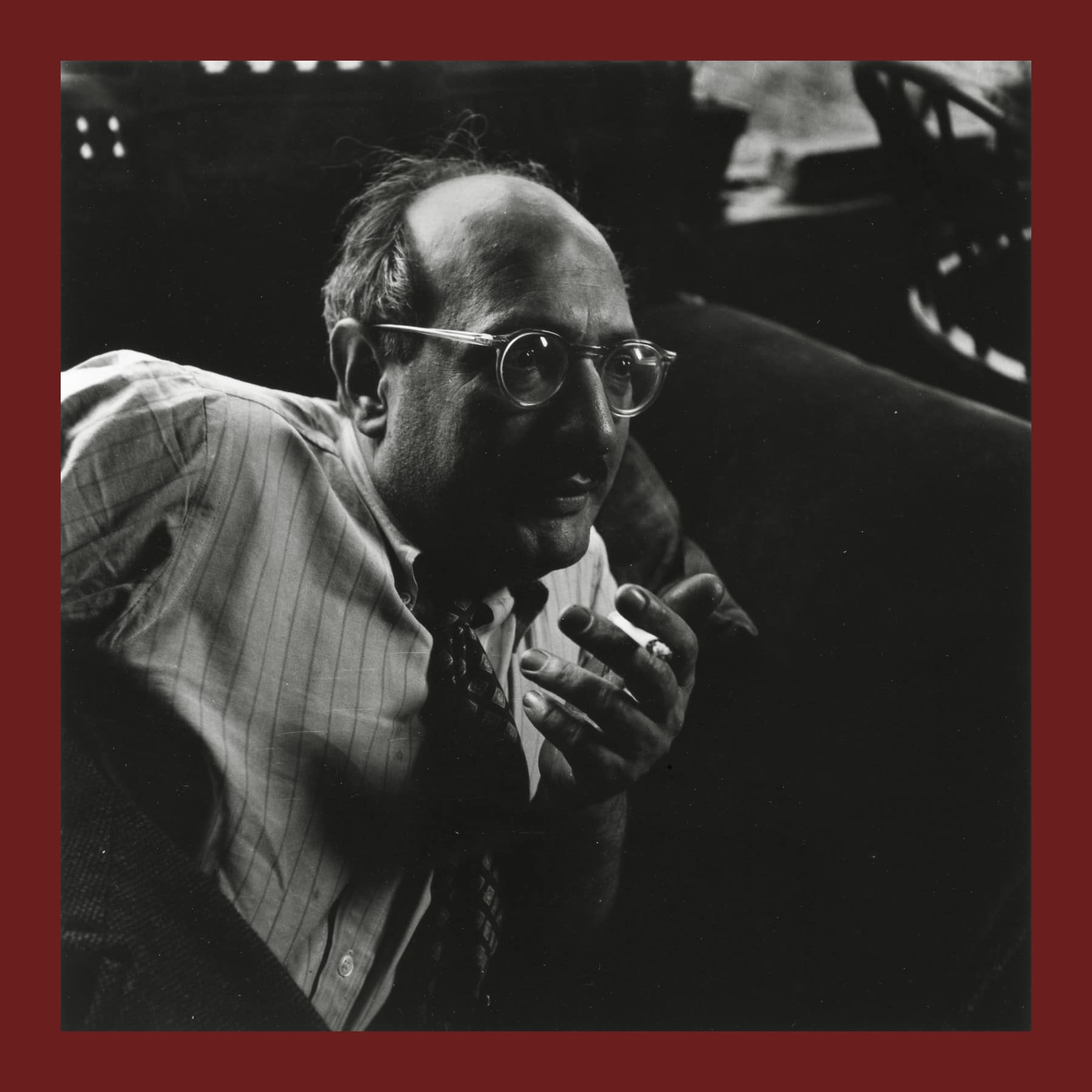 Black and white photo of Mark Rothko in glasses and a striped shirt, smoking a cigarette