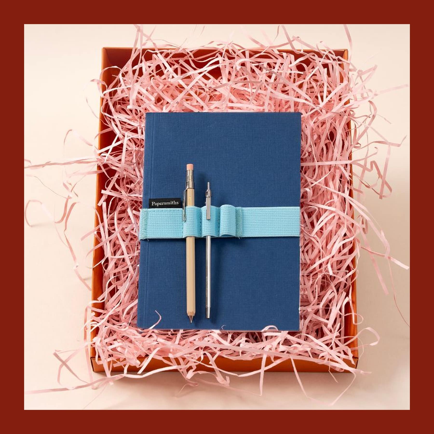 Papersmiths Travellers Gift Set with a blue notebook, pen and pencil in pink shredded paper