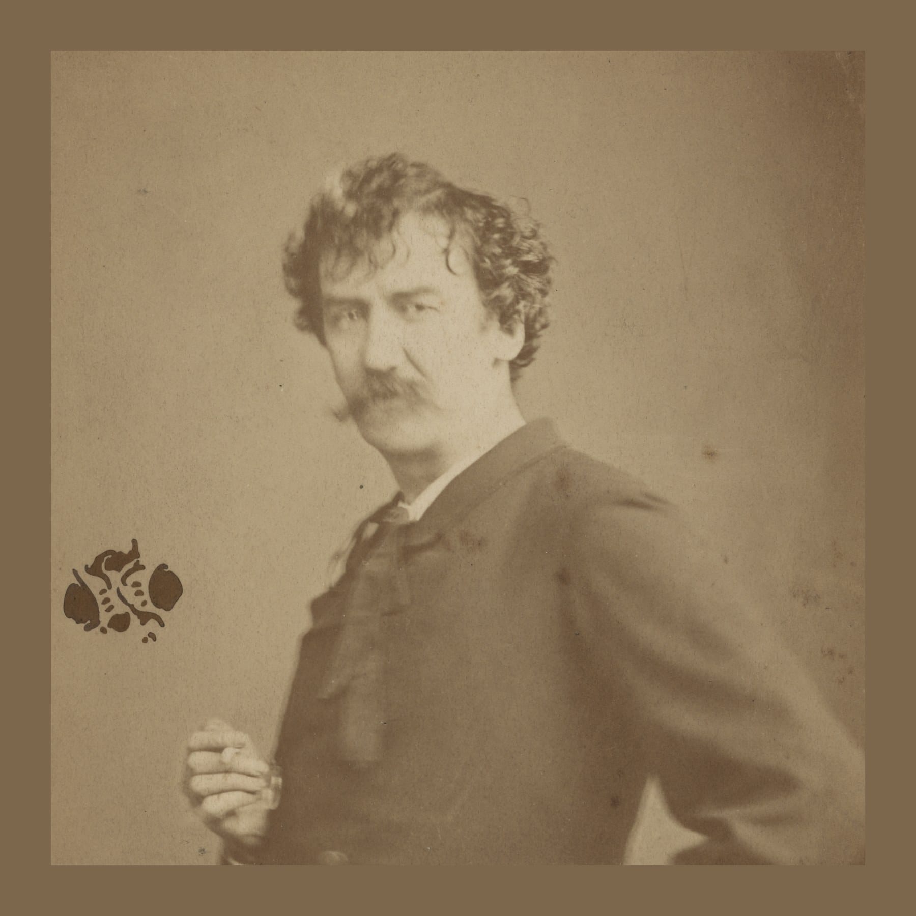 Sepia photograph of James McNeill Whistler with curly hair and a moustache, holding a cigarette, his butterfly monogram beside him