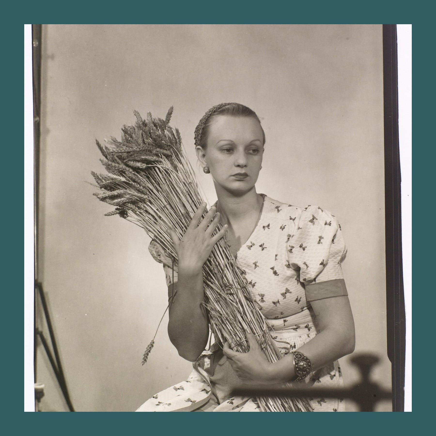 Black and white photograph of Ithell Colquhoun in a patterned dress, holding a sheaf of wheat