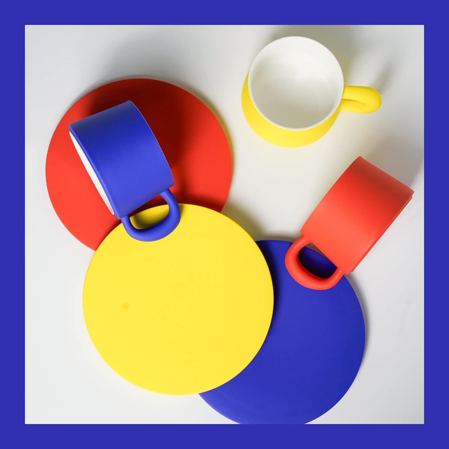 Blue, red and yellow 16kai Ideal porcelain cups with matching round saucers on a white surface