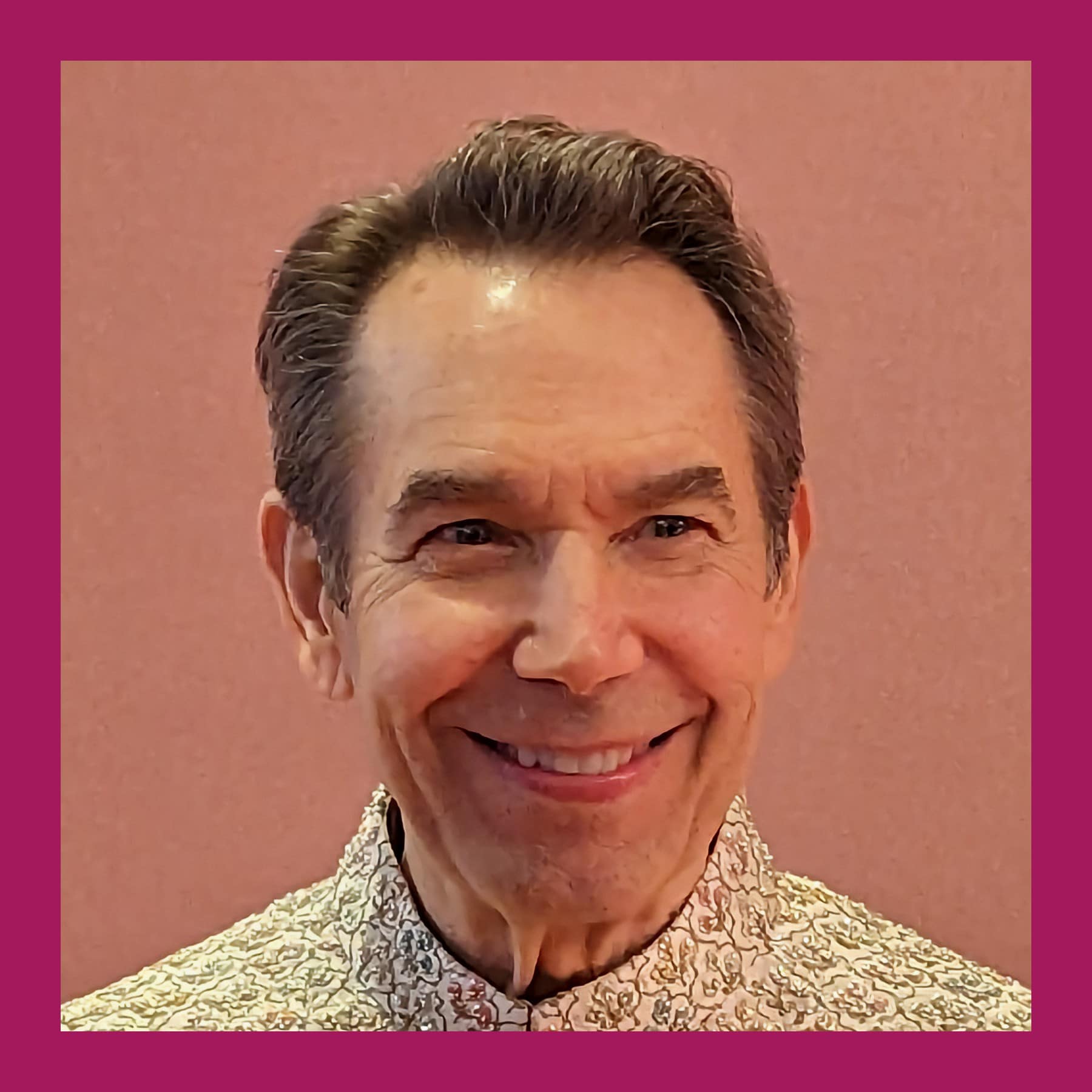 Jeff Koons smiling, in an embroidered high-collar jacket, against a pink wall
