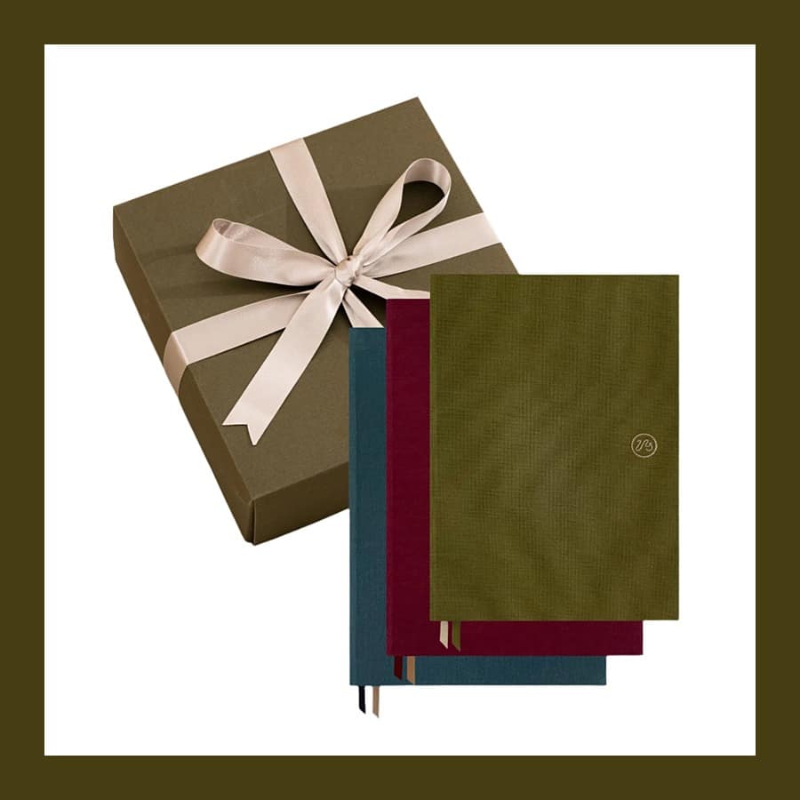 Three Papersmiths Clifton A5 notebooks beside a gift box tied with ribbon