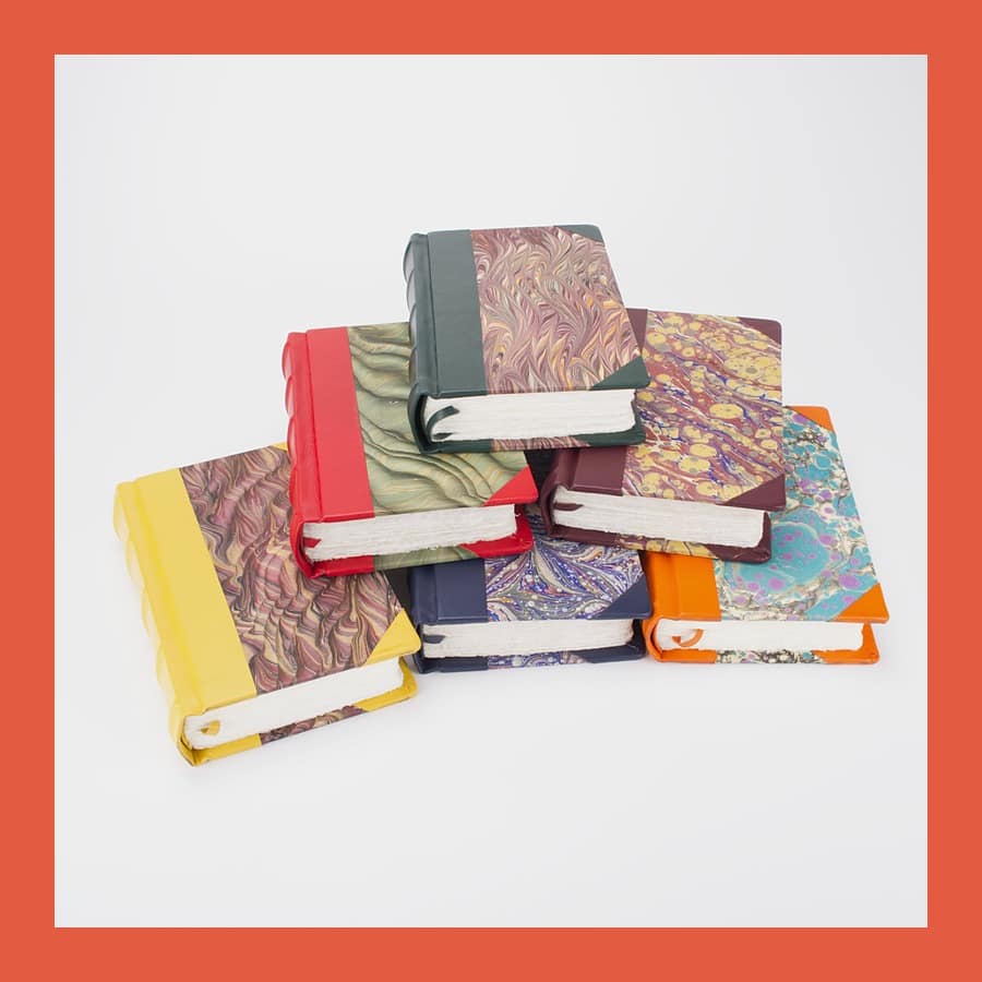 Stack of Bobbio handmade marbled journals with coloured leather spines