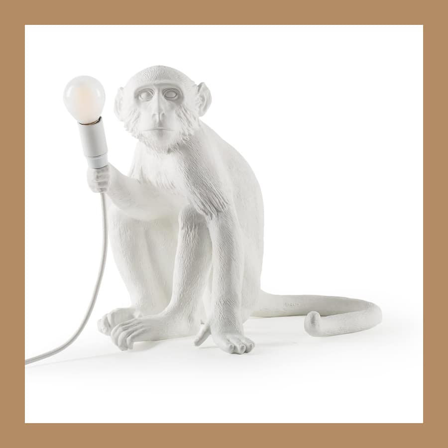 Seletti Monkey Lamp sitting version in white resin holding a lit bulb