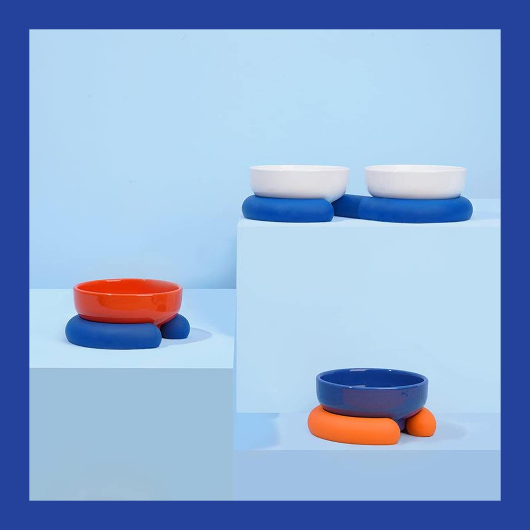 ZEZE ceramic pet bowls in orange, white and blue on chunky blue and orange silicone bases, on pale blue blocks