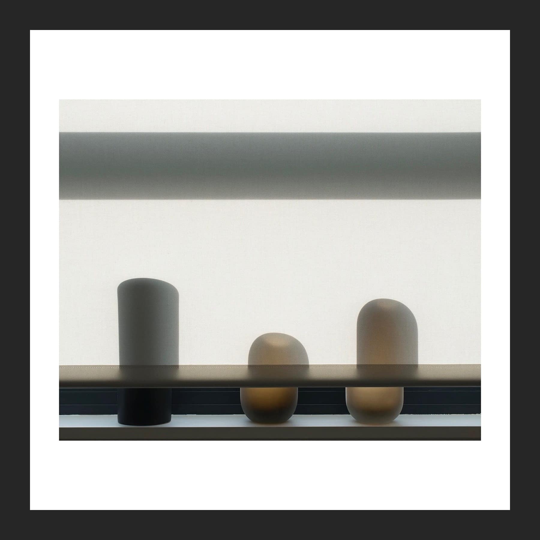 Photograph of three soft-edged pots on a window sill, silhouetted against a pale roller blind