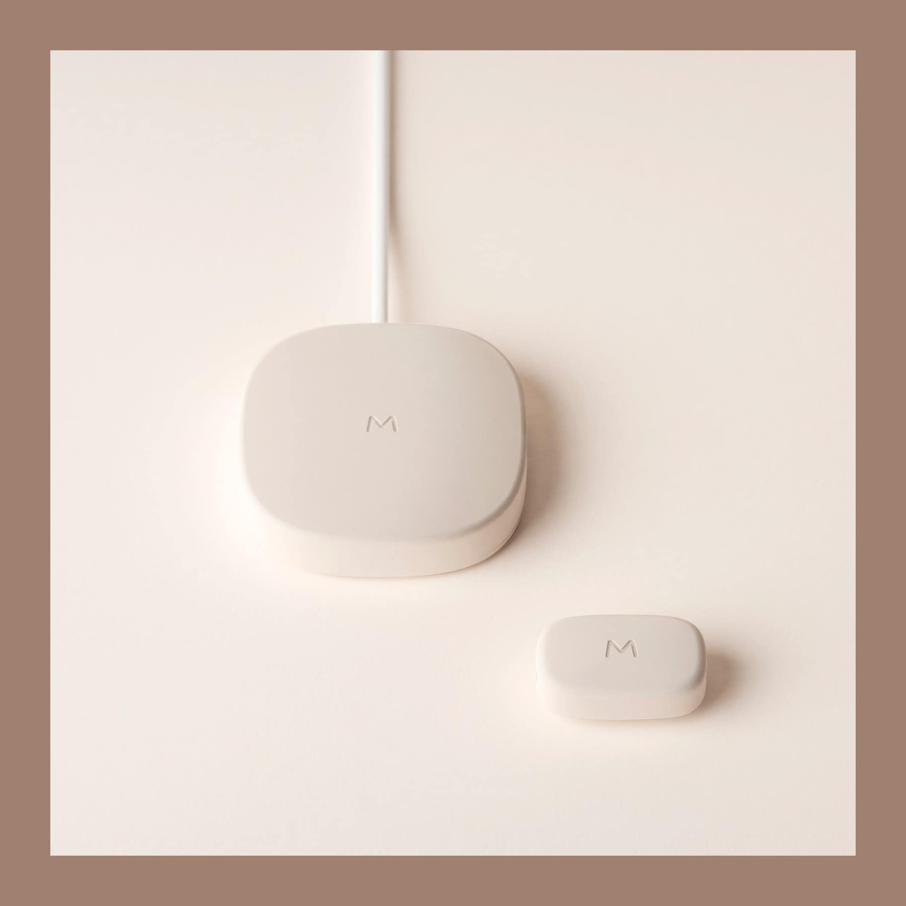 Moggie cat activity tracker beside its round charging hub on a cream surface