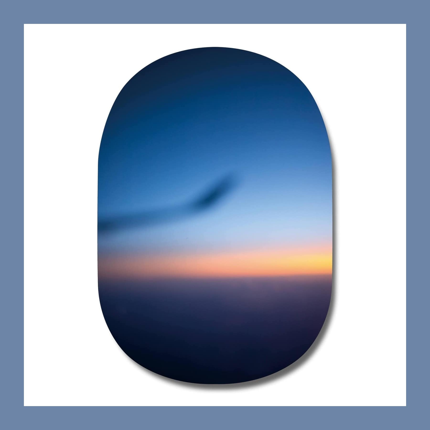 Rounded, window-shaped photograph of a blurred blue dusk sky with an orange band on the horizon
