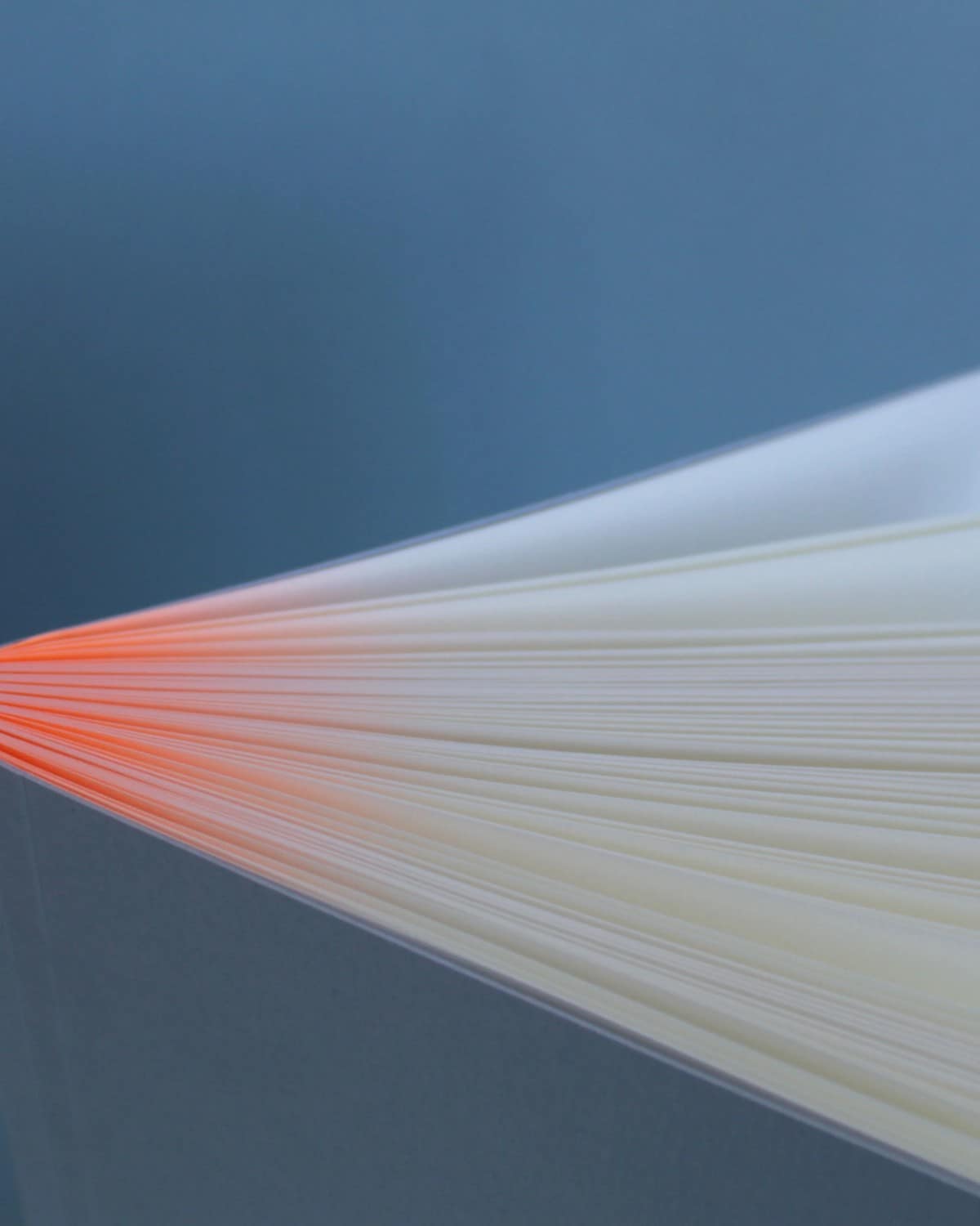 The Mark+Fold Glow notebook's page block fanned open, with neon orange running along the bound edge