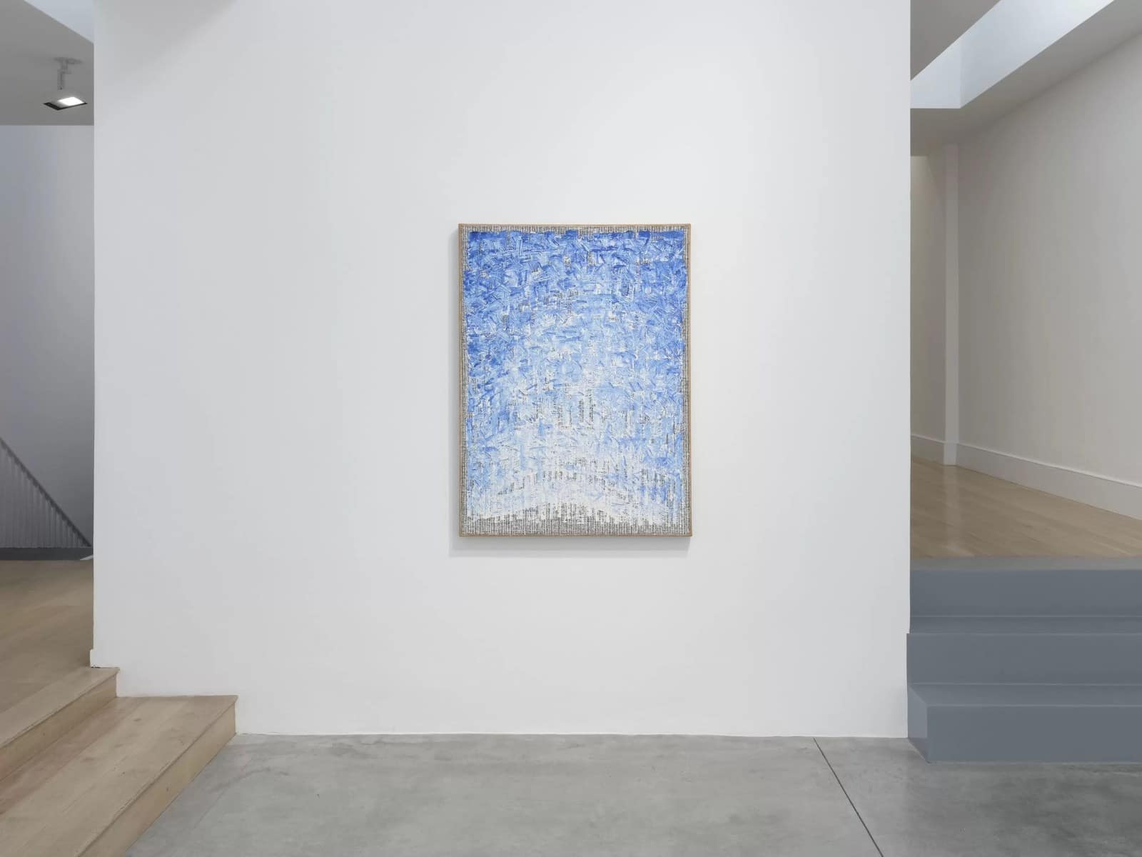 A pale blue Ha Chong-Hyun painting on hemp canvas hanging by a staircase at Lisson London