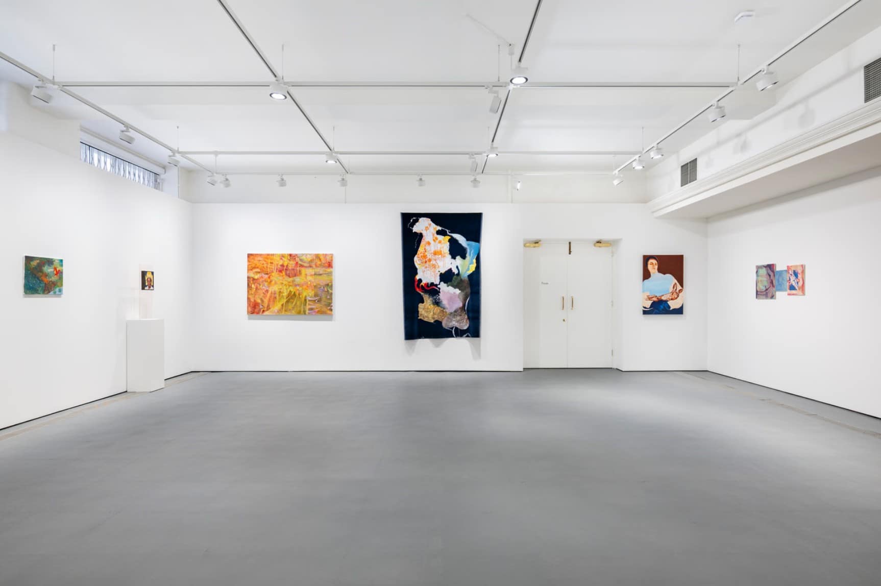 A white gallery at Freelands Foundation with paintings spaced around three walls, a dark velvet hanging and a small portrait on a plinth
