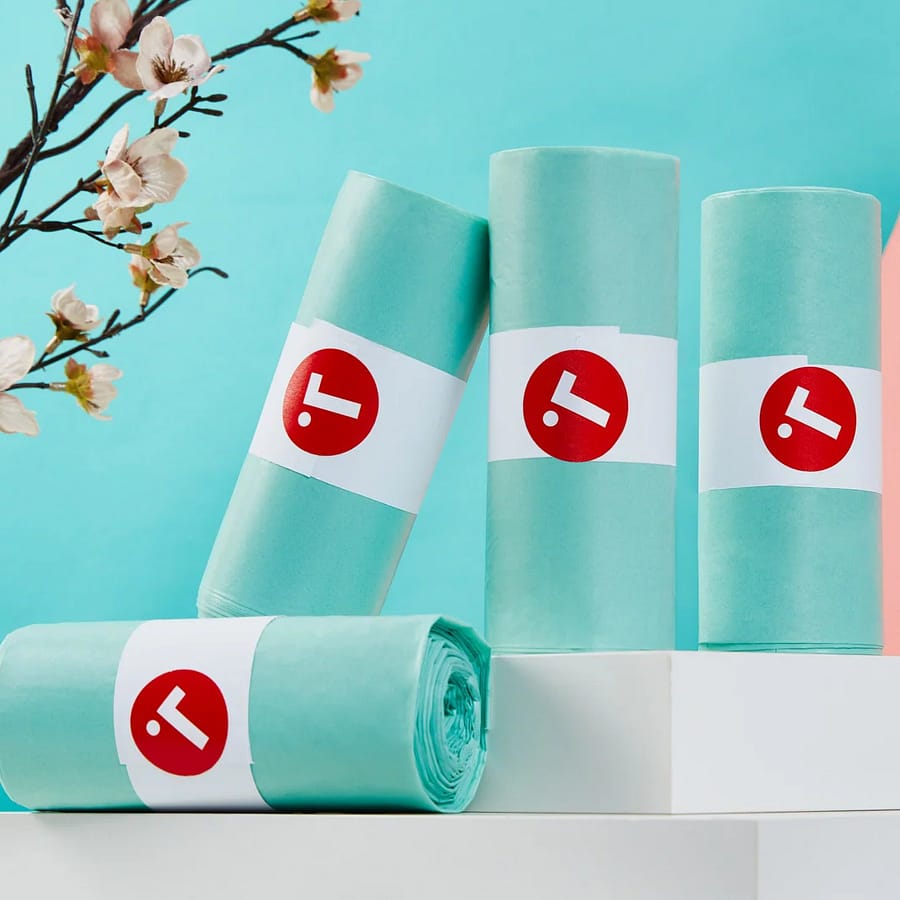 Four rolls of teal Toraphene compostable caddy liners on a pale blue background