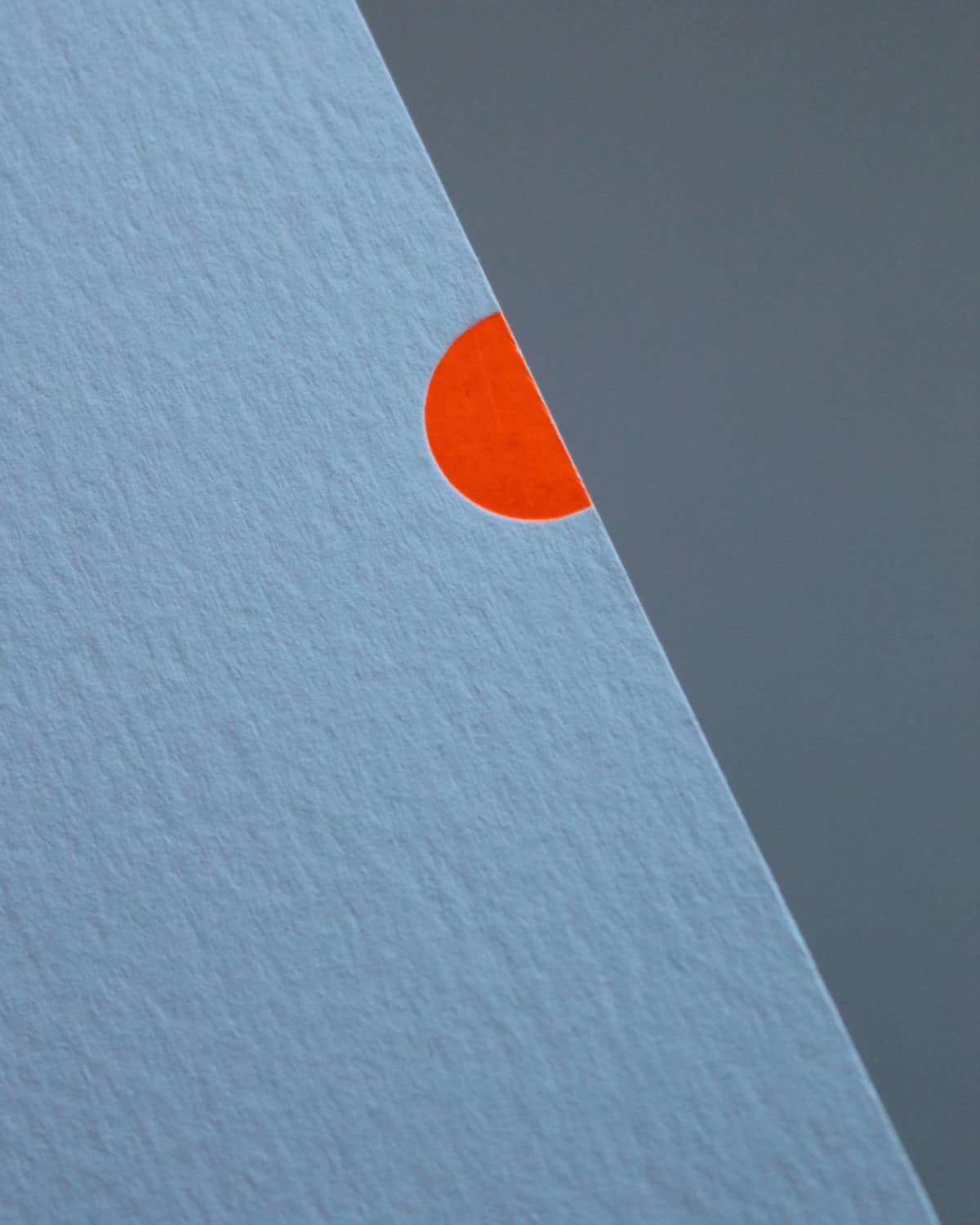 Close-up of the grey Mark+Fold Glow notebook cover with a small neon orange foiled half-circle on its edge