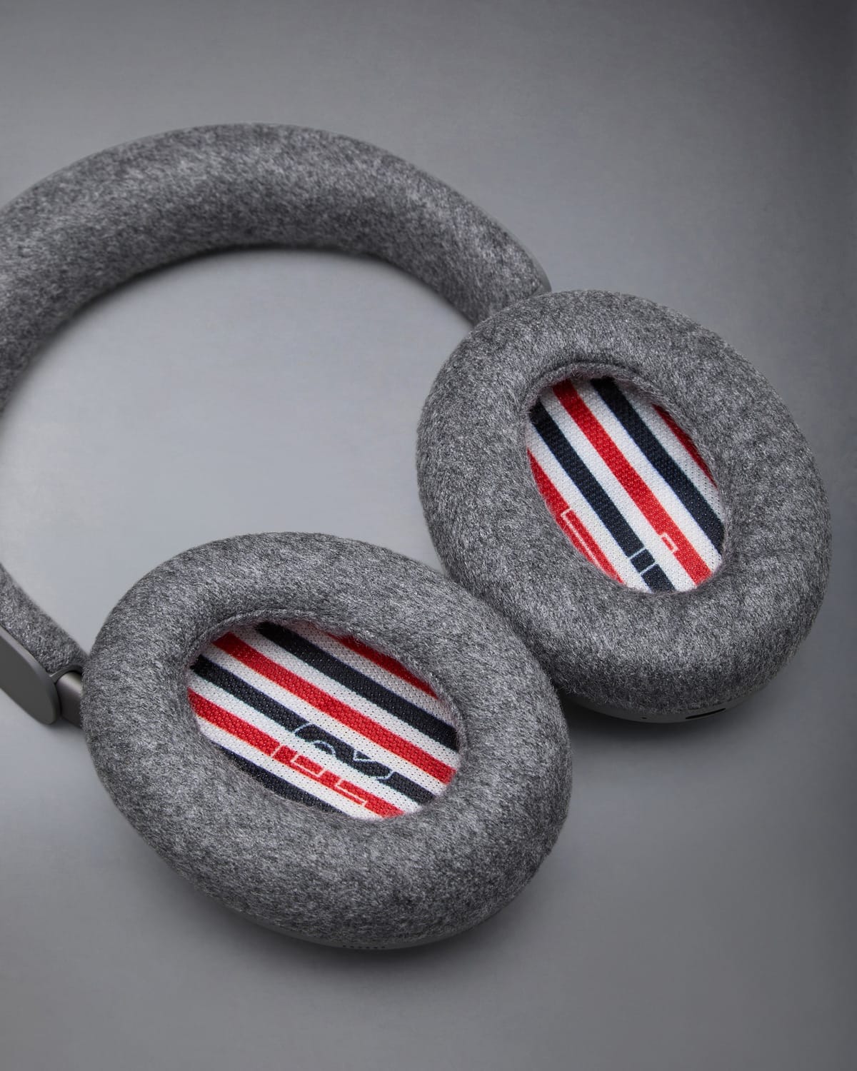Two grey cashmere Bose ear cushions, each lined with red, white and navy stripes