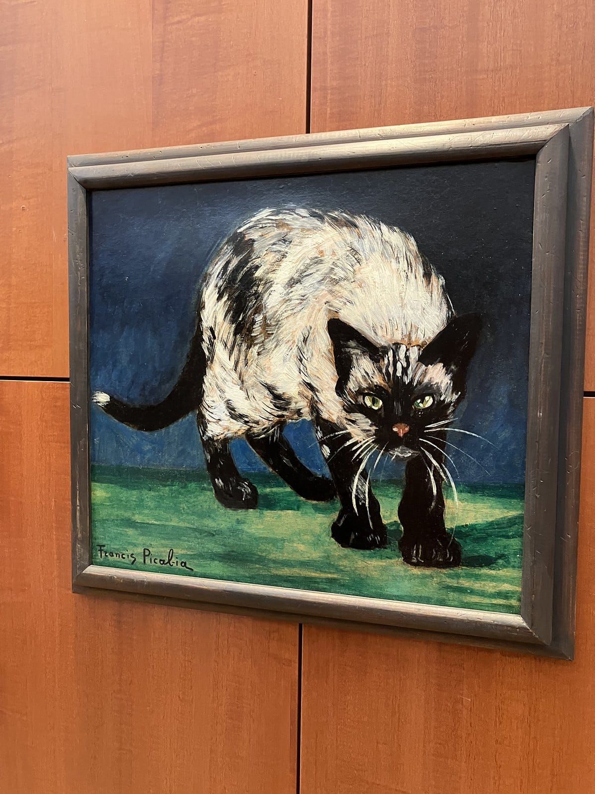 Francis Picabia painting of a black and white Siamese cat in a dark frame on a wood-panelled wall