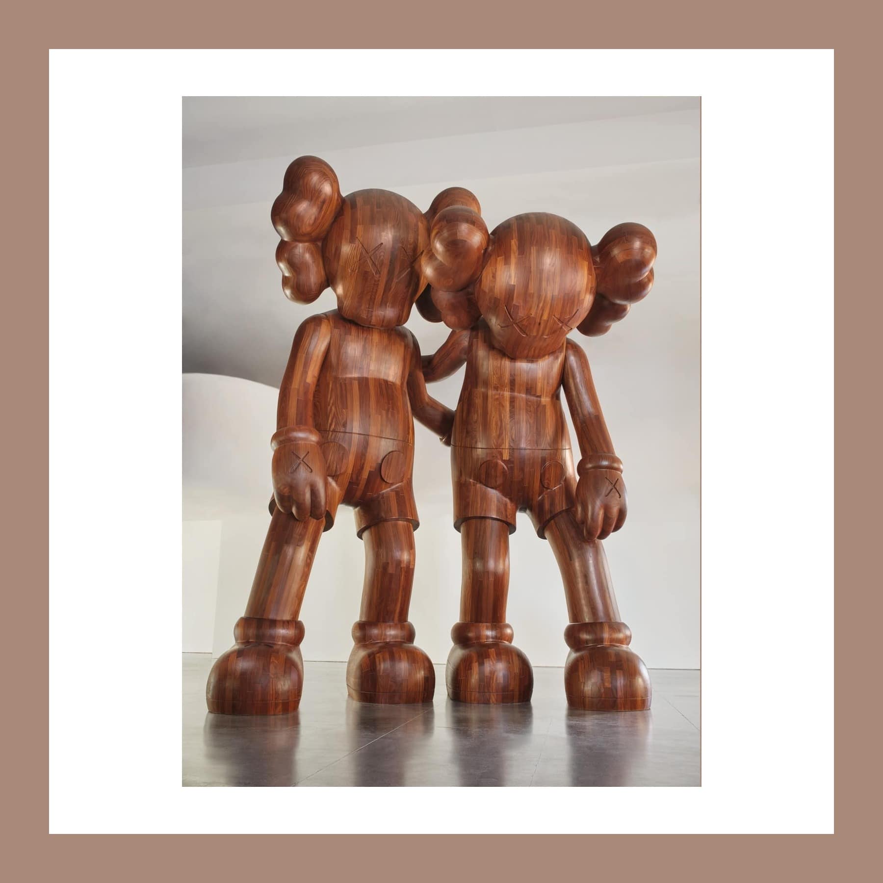 Two towering wooden cartoon figures with crossed-out eyes stand side by side, one with its arm round the other