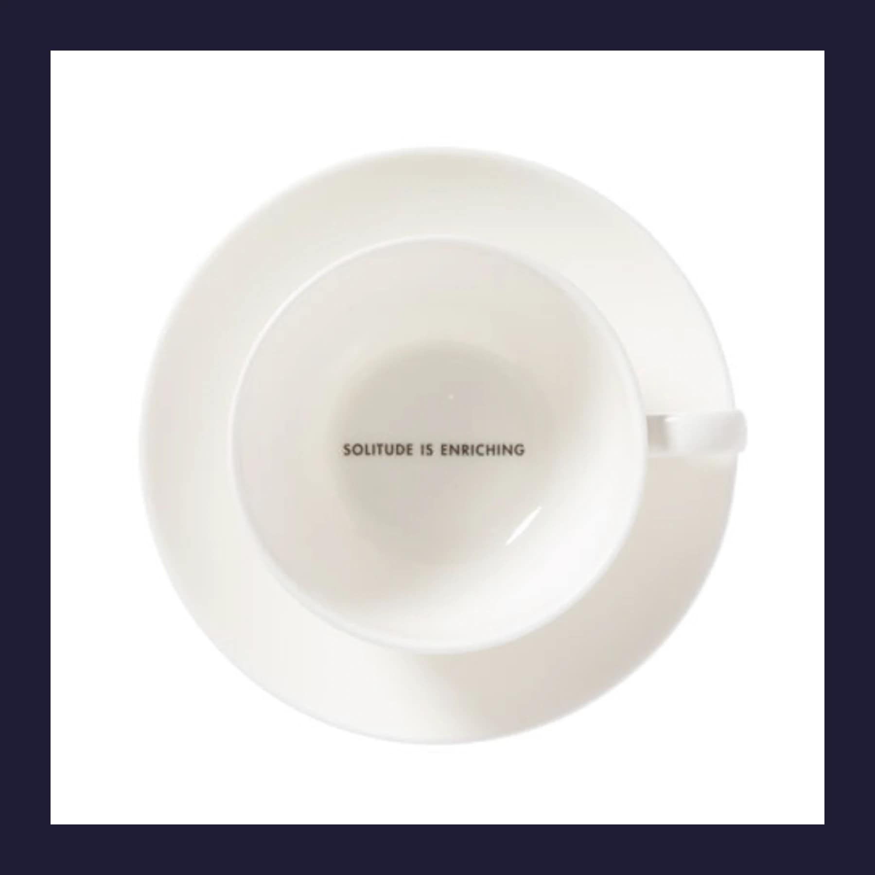 White bone china teacup and saucer with Solitude Is Enriching printed inside, viewed from above