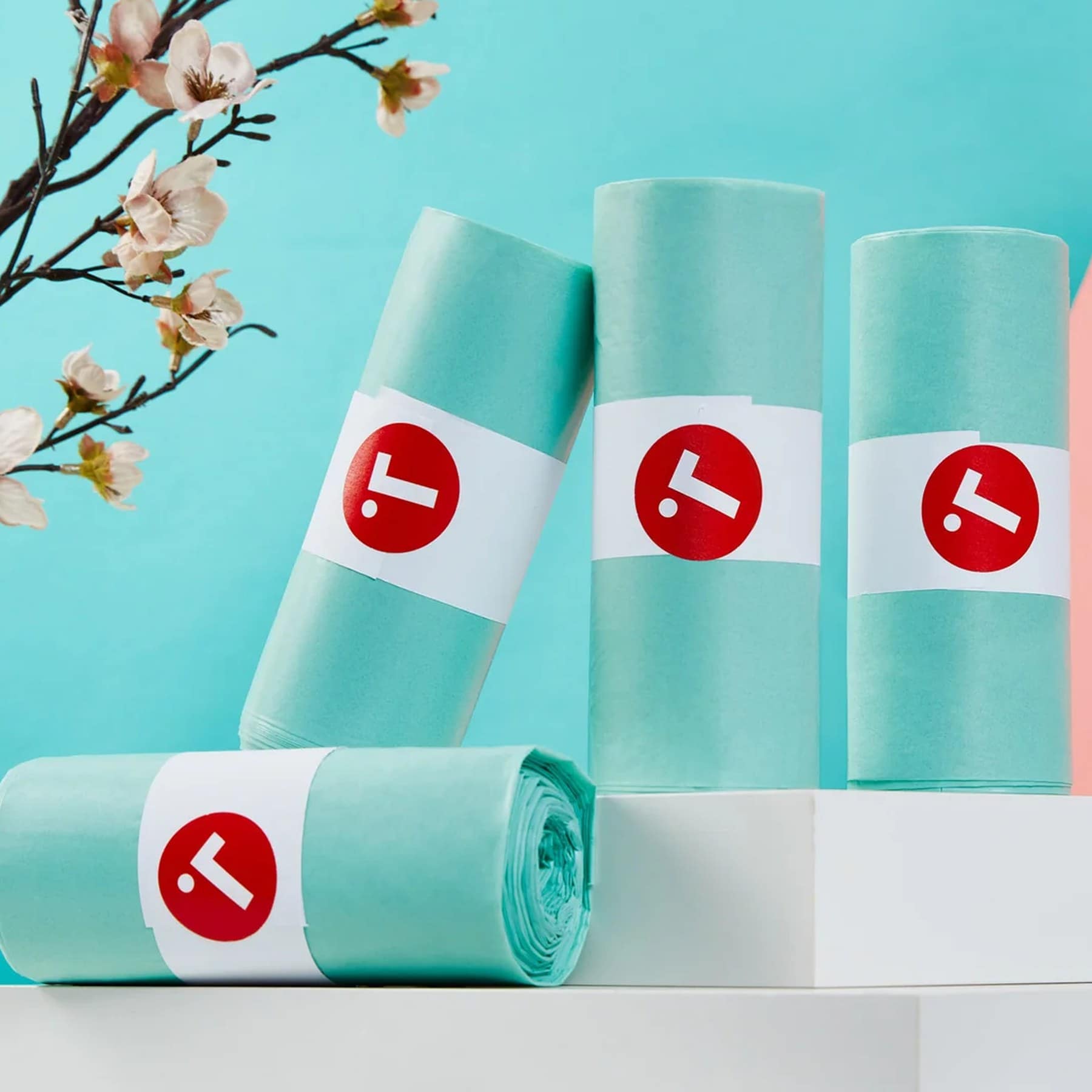 Four rolls of teal Toraphene compostable caddy liners on a pale blue background