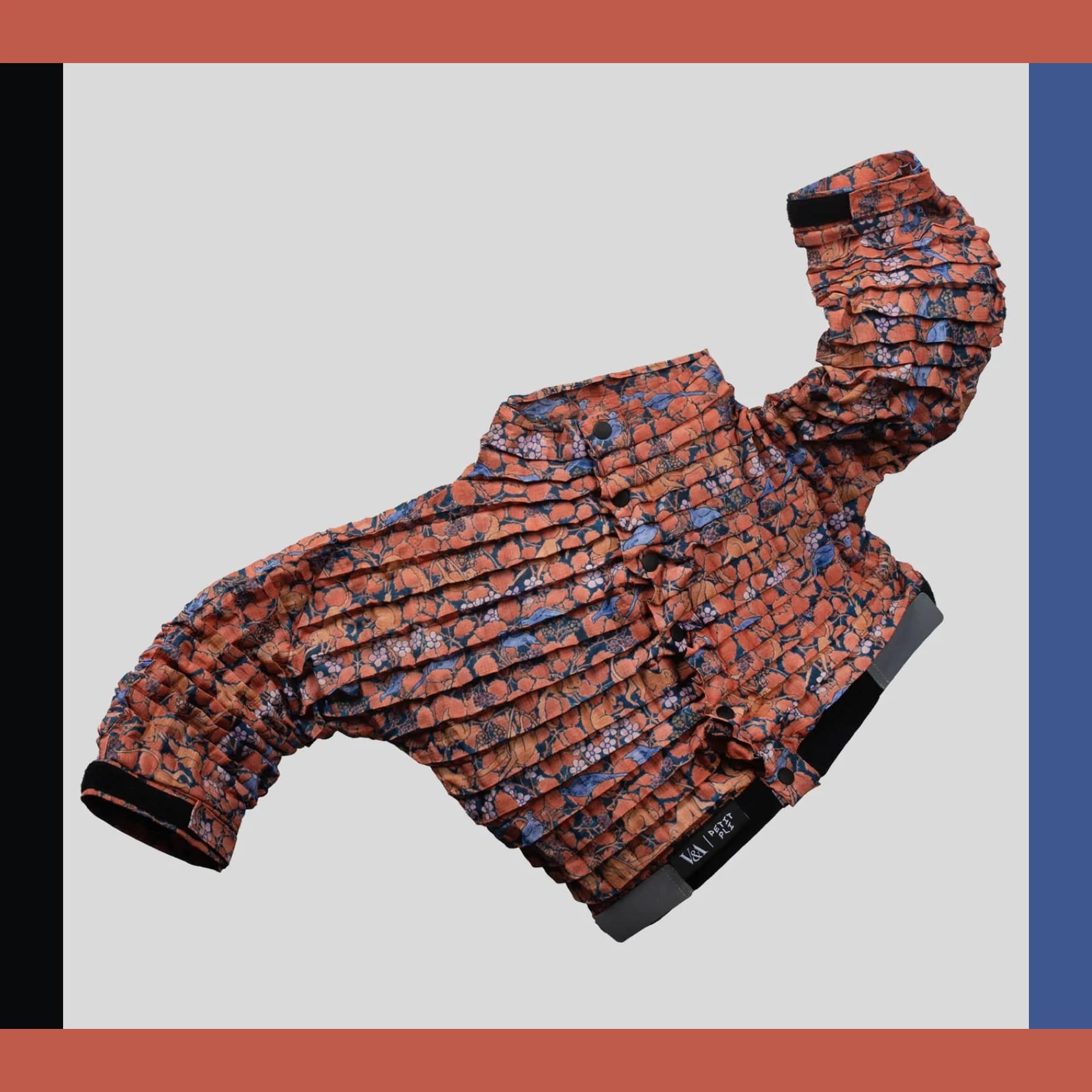 Petit Pli discount code promo image of a pleated kids jacket in orange and blue print on a grey background