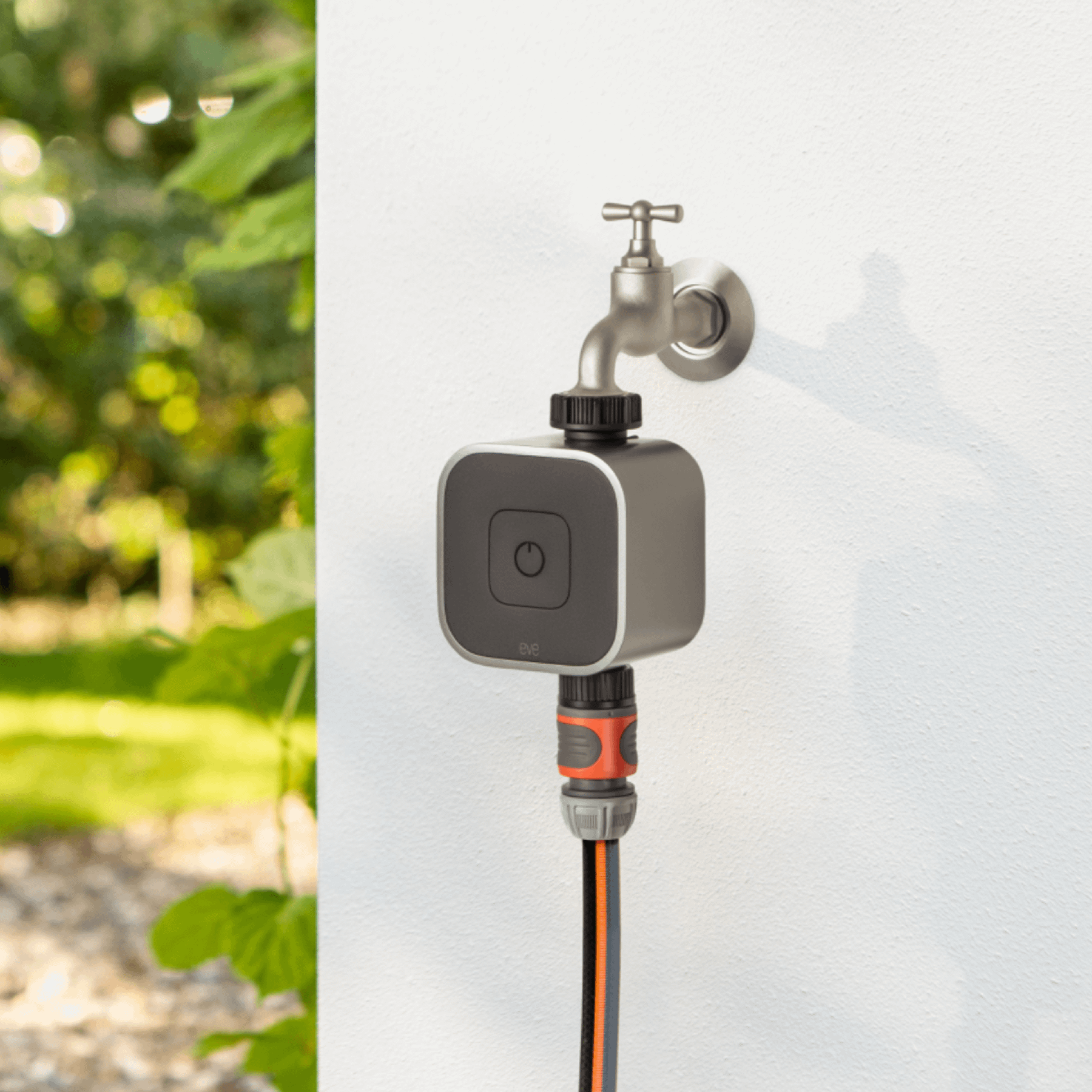 Eve Aqua smart tap timer fitted between a UK outdoor tap and a garden hose connector