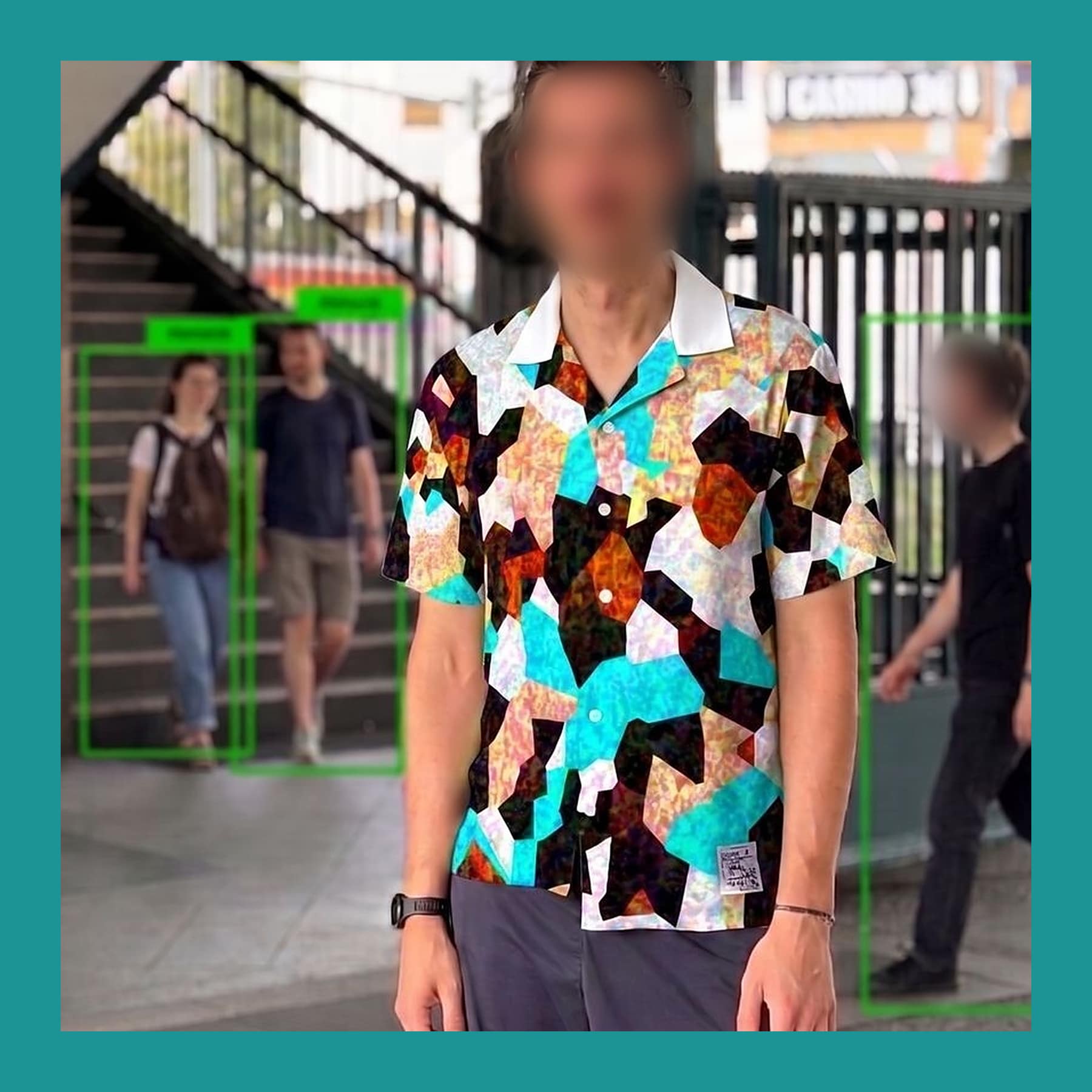 Man in the Digital Camouflage shirt at Kottbusser Tor, unlabelled while nearby pedestrians carry green person boxes. Faces blurred.