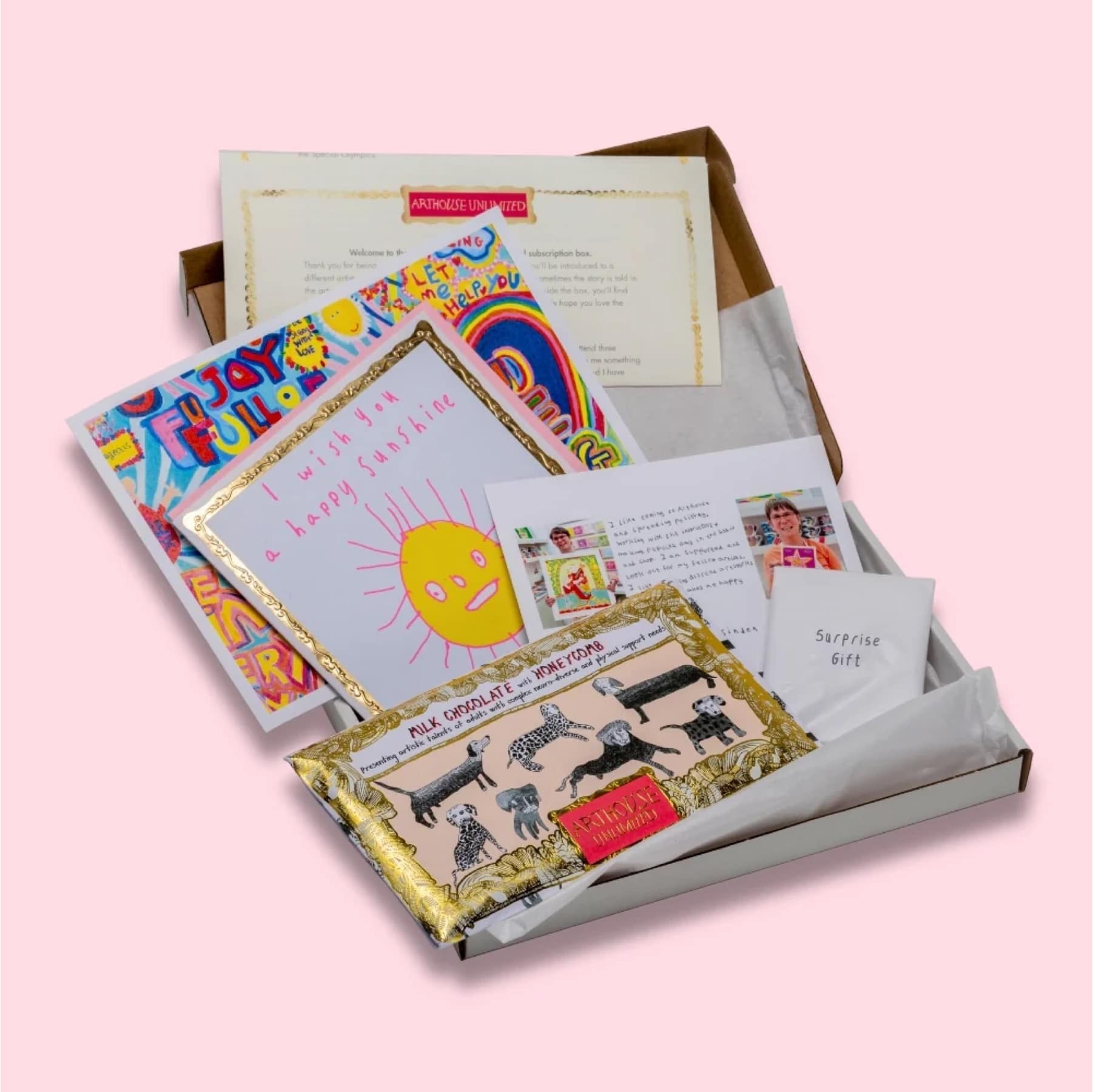 ARTHOUSE Unlimited Letterbox Love box open on pink, with colourful artist prints, a chocolate bar and a surprise gift envelope