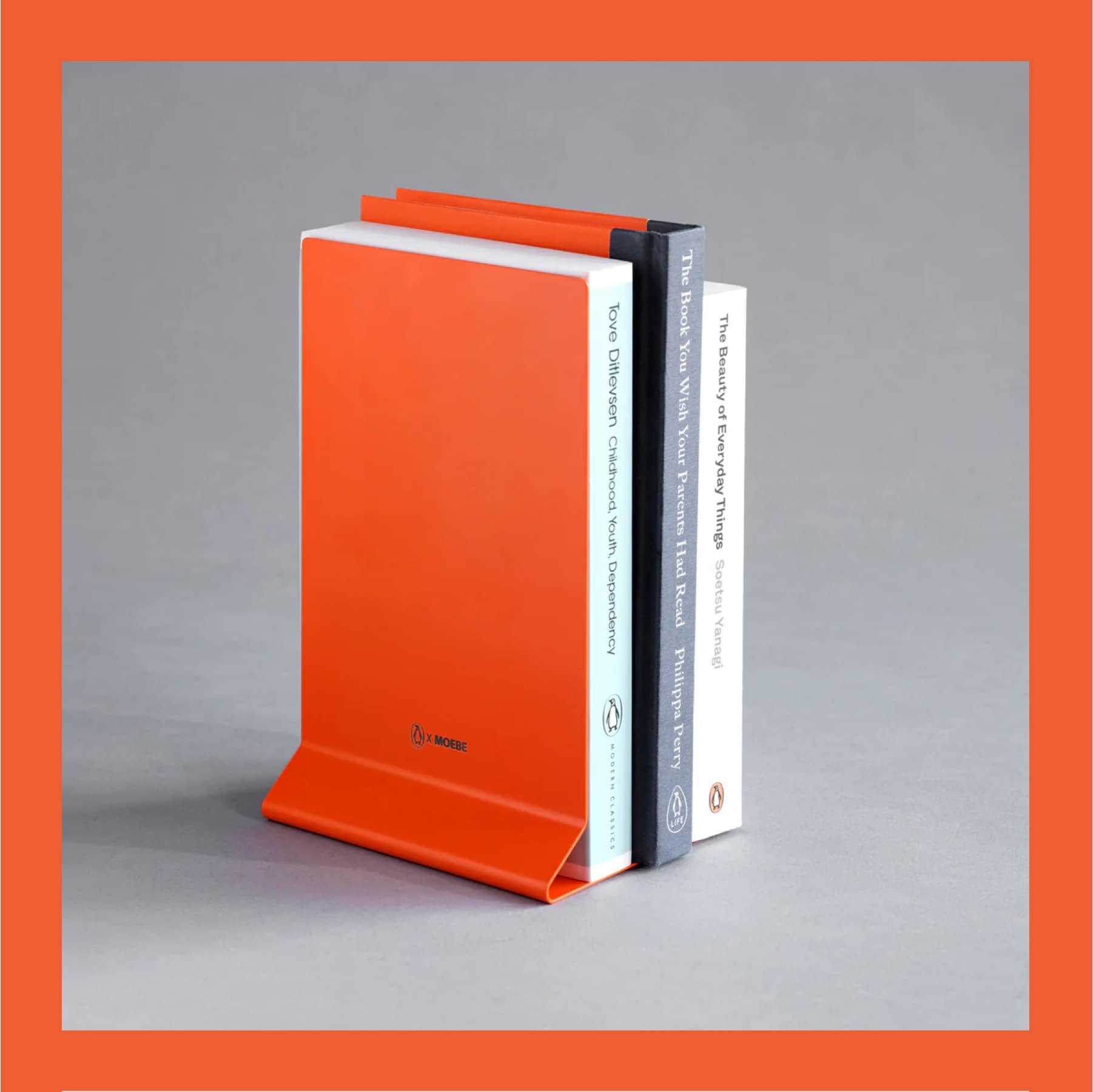 Penguin x MOEBE Book Stand in Penguin orange propping up several upright books