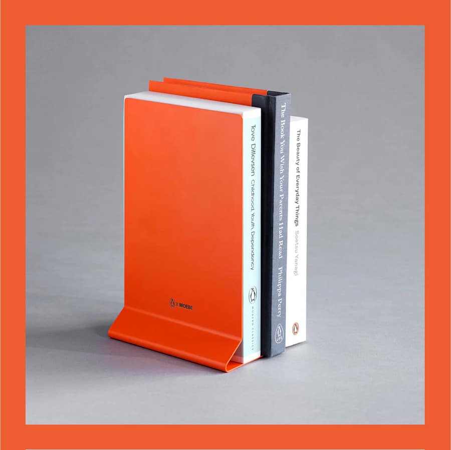 Penguin x MOEBE Book Stand in Penguin orange propping up several upright books