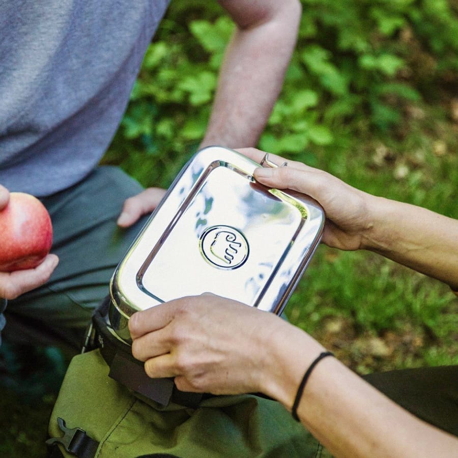 Hands holding an Elephant Box stainless steel lunchbox outdoors, perfect for eco-friendly lunches