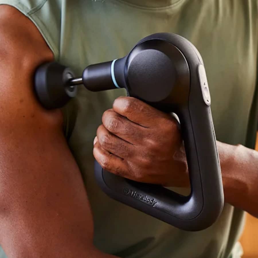 Theragun Prime massage gun on upper arm for deep tissue relief