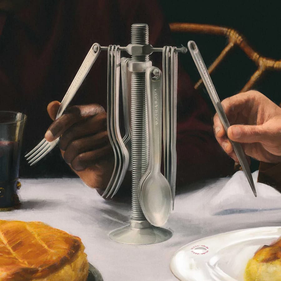 Alessi Conversational Objects cutlery set displayed on a dining table with two people using the utensils