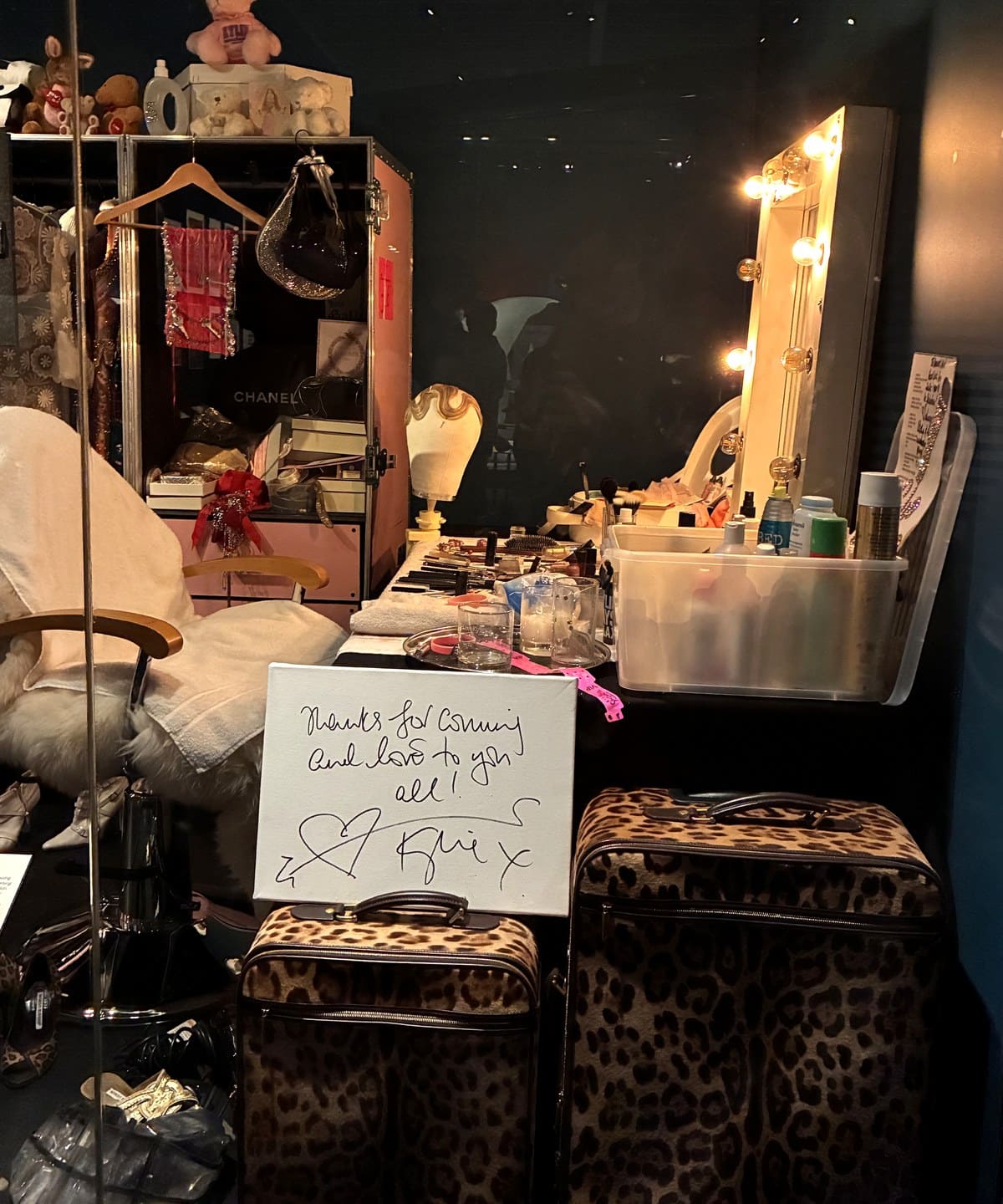 Recreation of Kylie Minogue's dressing room at the V&A with a lit mirror, leopard print cases and a handwritten card