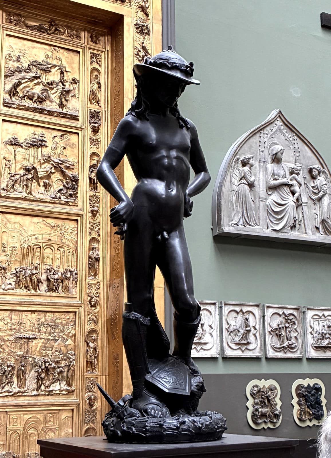 Cast of Donatello's bronze David wearing a laurelled hat and boots, standing over the head of Goliath